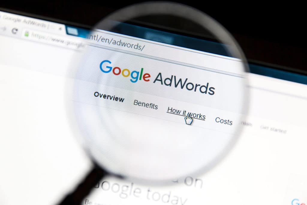 une loupe montre une page Google AdWords sur un écran d'ordinateur.