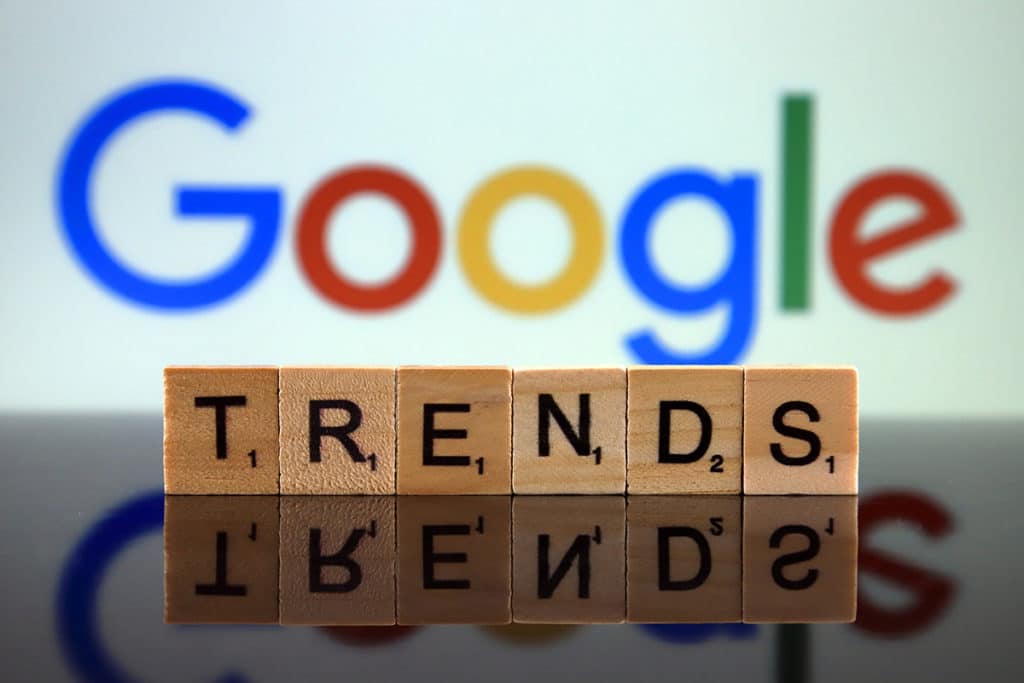 Le mot "trends" ecrit en cube de bois devant le logo de google. Pour signifier "google trends"