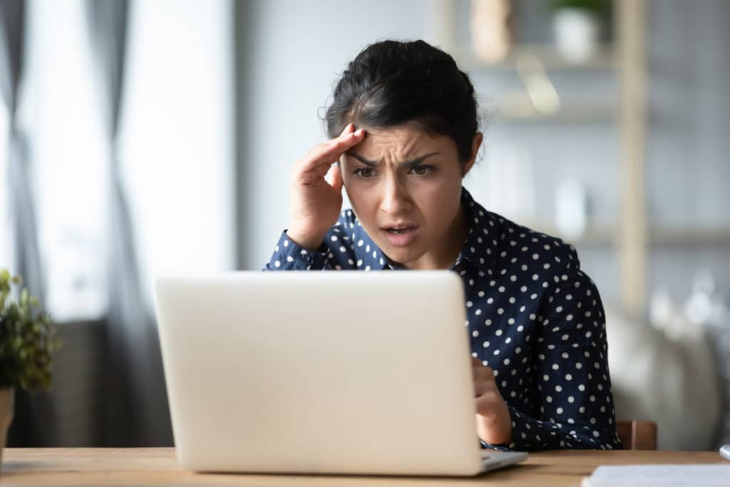 une jeune femme stressée regardant l'écran d'un ordinateur portable, touchant le front, une fille agacée et frustrée par un problème