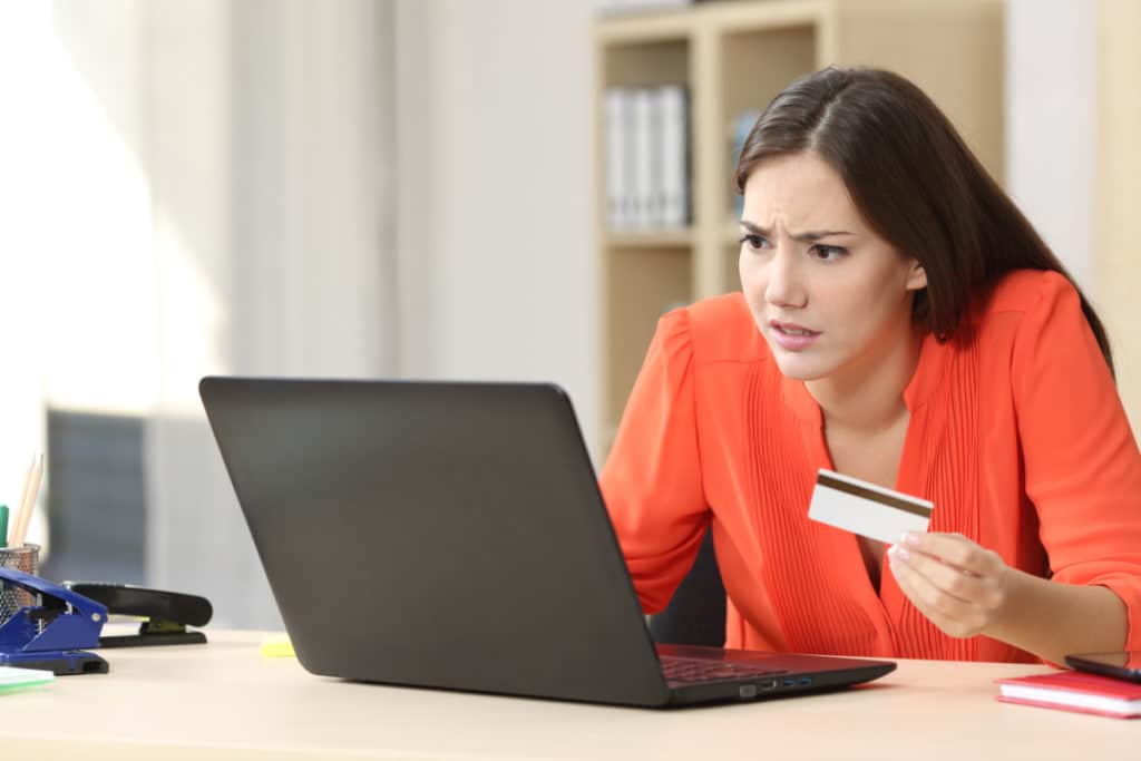 acheteuse inquiète des problèmes d'acheter en ligne avec une carte de crédit et un ordinateur portable dans un petit bureau