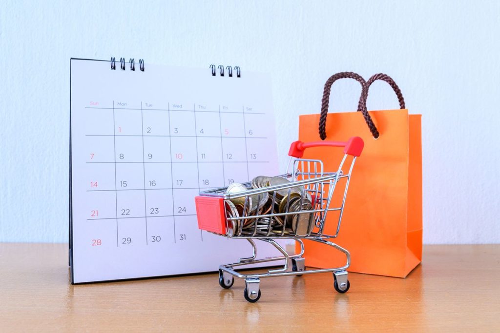 Une photo d'un calendrier marketing avec un caddie remplis d'article et un grand panier de shopping