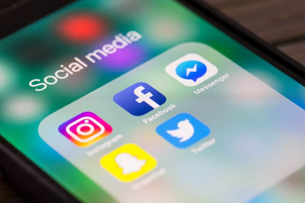 le dossier "Social media" d'un téléphone mobile est en gros plan avec les diverses apps des réseaux sociaux : "Instagram, Facebook, Messenger, Snapchat, Twitter".
