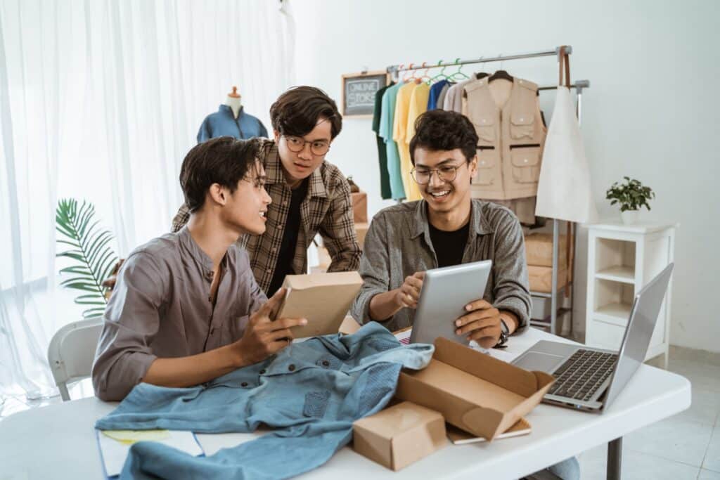 Trois hommes asiatiques discutant de produits vestimentaires.
