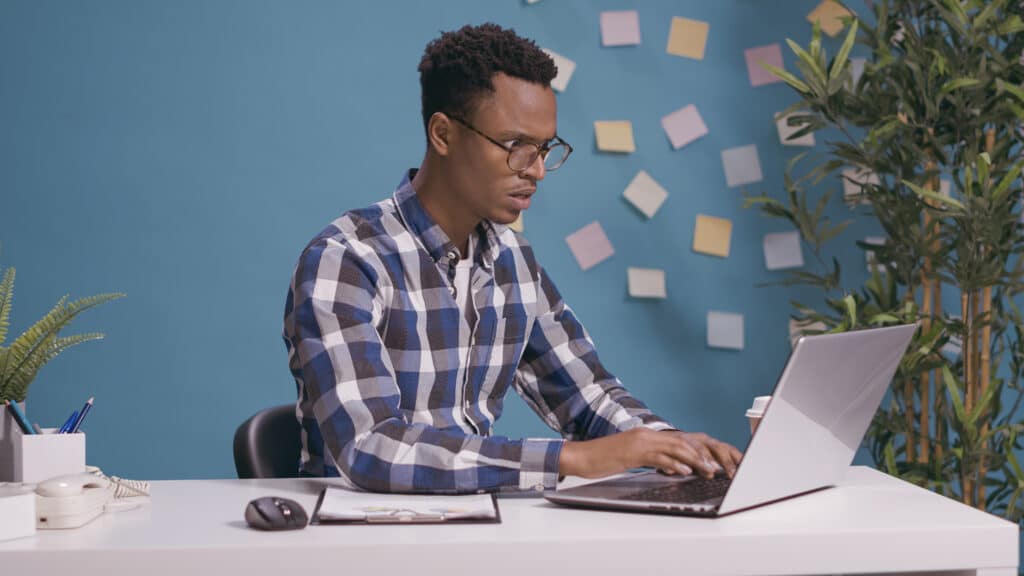 Photo d'un homme assis à son bureau devant un ordinateur portable se demandant comment s adapter à Spambrain de Google