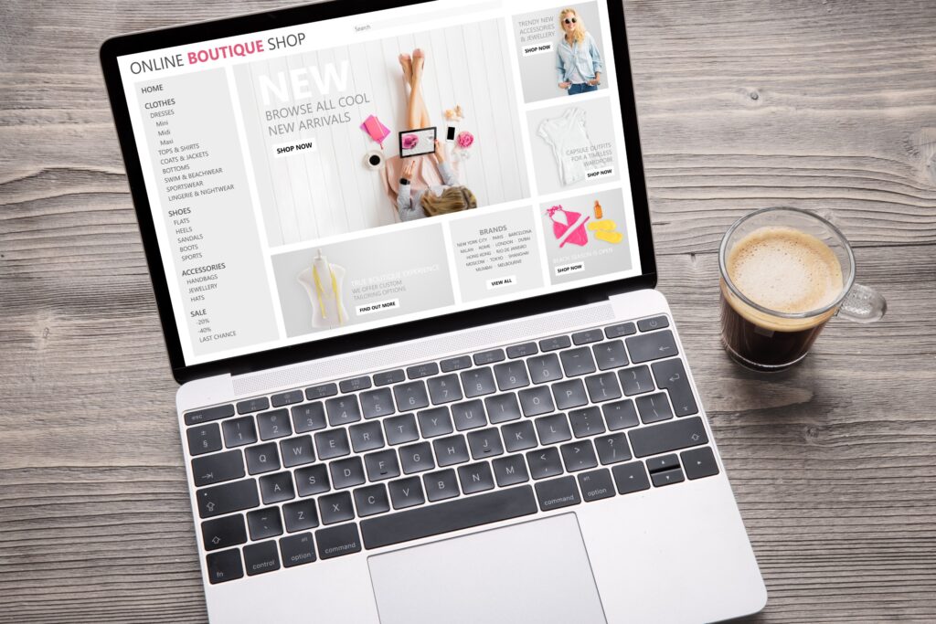 Un site de commerce en ligne affiché sur l'écran d'un ordinateur portable posé sur une surface en bois à côté d'une tasse de café.