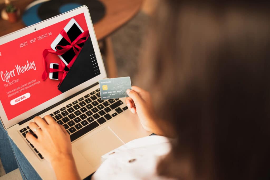 Une femme tenant une carte de crédit devant un ordinateur avec une publicité de couleur rouge